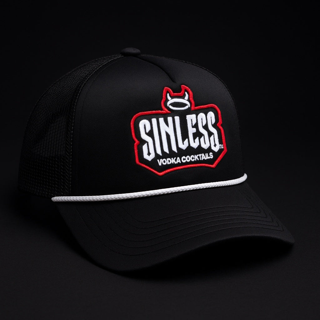 A side view of a black trucker hat against a black background. The Sinless logo is written in white across the front of the hat. Vodka cocktails is written under the logo in white. The logo is outlined in red. There is a halo with devil horns at the top of the logo. 